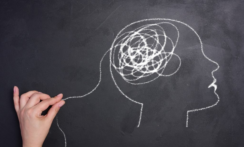 La psychologie de la cognition : explorer les mécanismes de la pensée humaine Profile of a human head with a tangled spiral in the brain area. The head is drawn in white chalk.