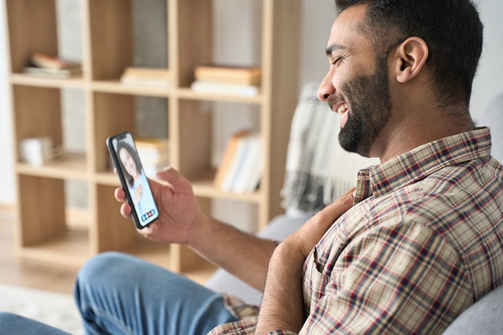Psychologie des sites de rencontre : Décryptage et astuces pour trouver l’amour en ligne Young handsome indian guy having videocall dating online.