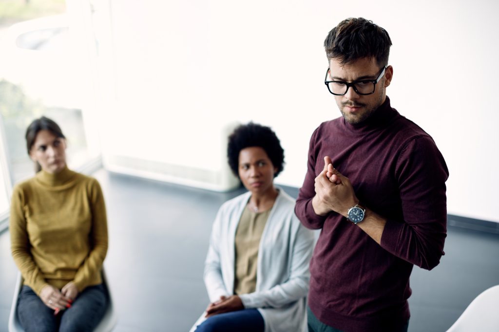 Anxious man talking about his issues during group therapy.