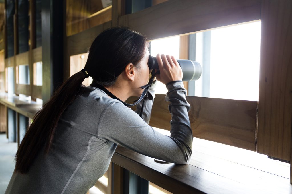 Asian Young woman looking though binoculars for birdwatching