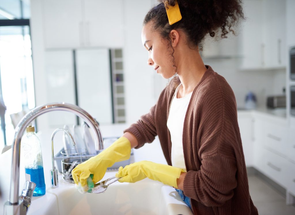 Because a dirty kitchen is a dirty house. Shot of a young woman washing the dishes at home.