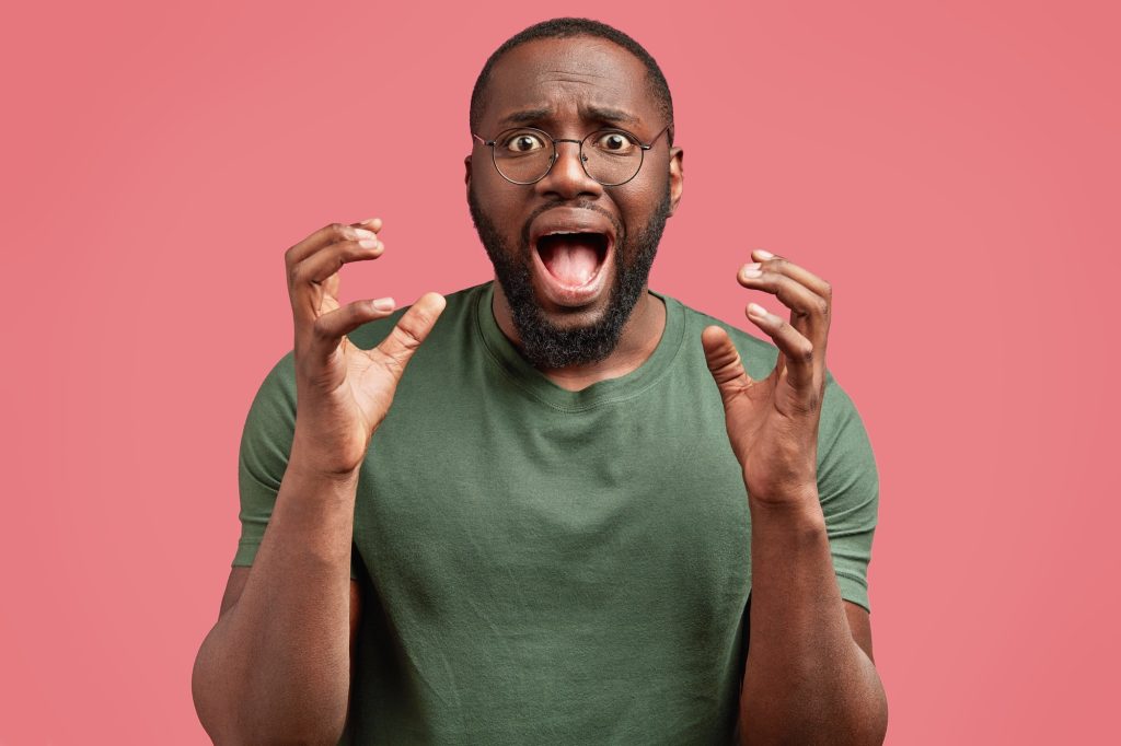 Monophobie : comprendre la peur d’être seul et ses impacts Horizontal shot of depressed mad African American male gestures actively and exclaims with fear, see