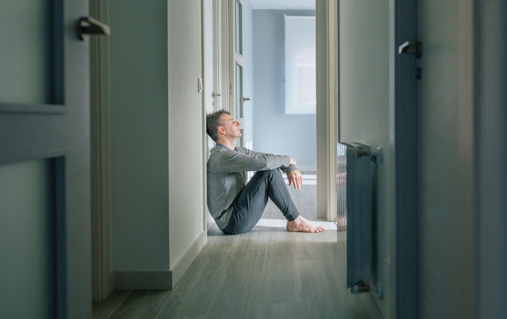 Comprendre la dépersonnalisation : causes et conséquences sur la santé mentale Man with mental disorder sitting on the floor