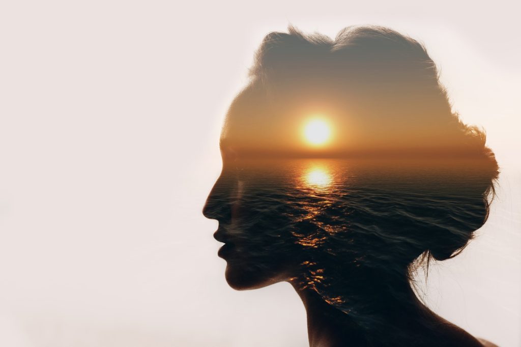 Comprendre la déréalisation et son impact sur la perception Multiple exposure sunrise and sea inside woman silhouette. Psychology concept