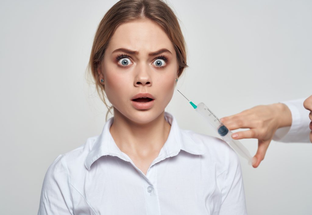 woman patient syringe in the hands of a doctor fear of injections phobia
