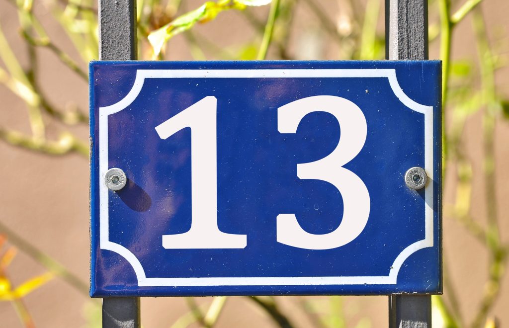 Closeup shot of a blue sign with the number 13 on the blurry background