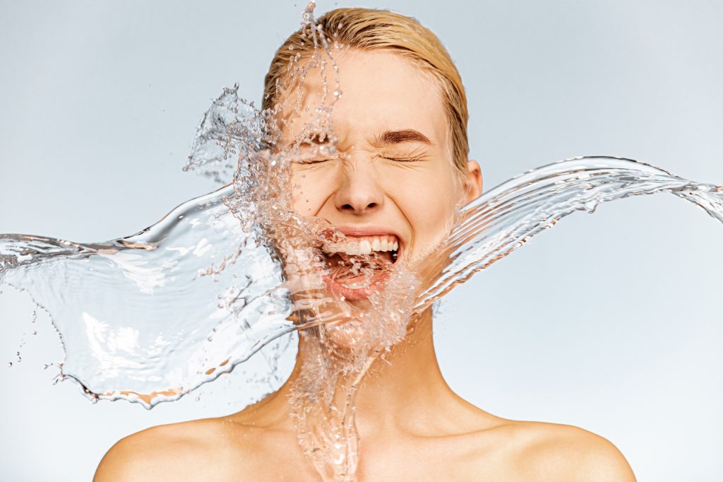 Photo of screaming woman with drops of water around her face.