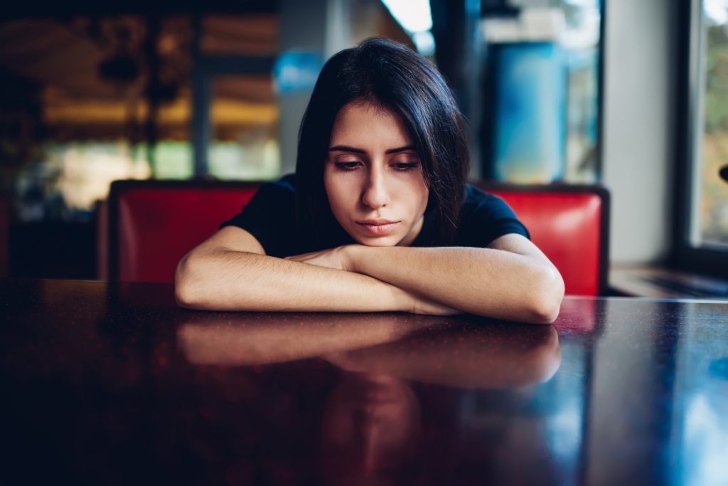 Sad woman leaning on table in cafe
