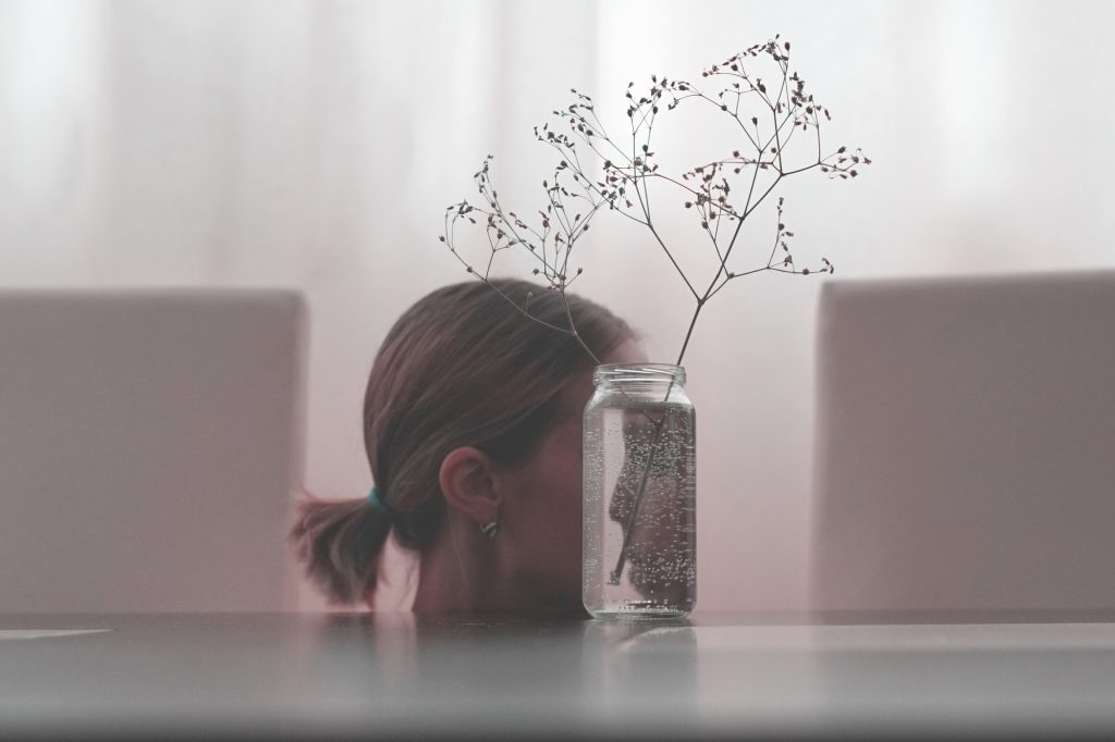 The girl's face reflected in a glass jar. Look into yourself. The psychological concept.