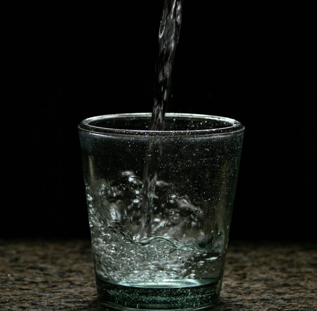 4 bienfaits insoupçonnés d’une bonne hydratation a glass of water with a black background
