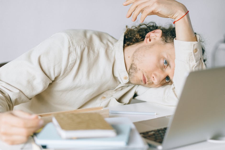 Professional exhausted worker at desk with laptop and papers