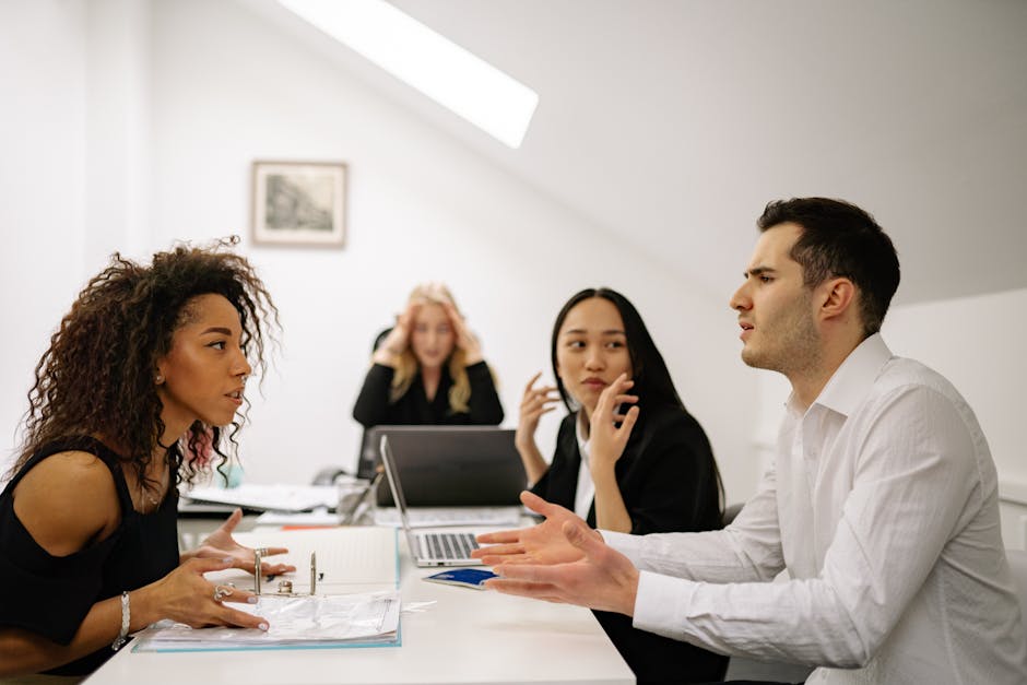 Groupe de collègues en discussion dans un bureau, avec une personne hésitante à parler