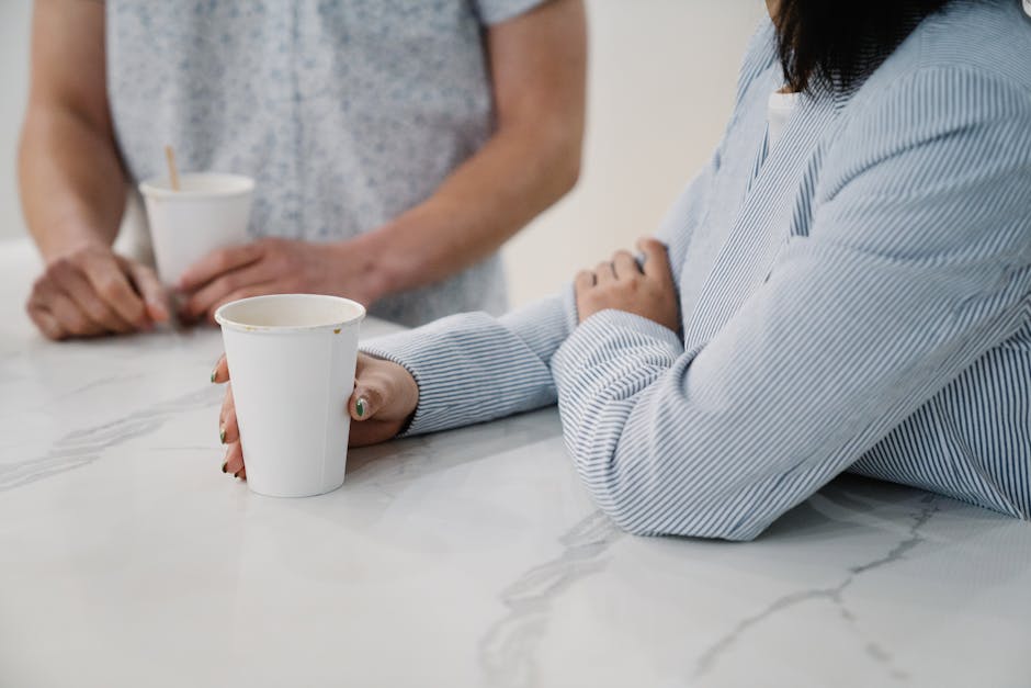 Small group of coworkers talking informally around a coffee machine in an office